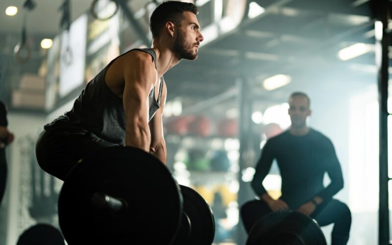 low-angle-view-muscular-build-man-doing-deadlift-while-exercising-with-barbell-gym_637285-2489